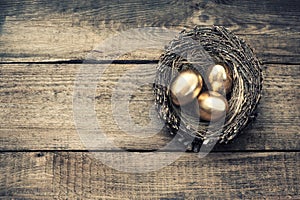 Golden easter eggs in birds nest vintage toned