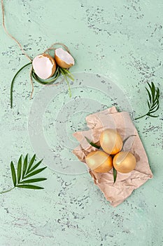 Golden easter eggs and green leaves on a stelo-blue background. photo