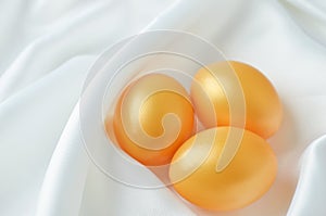 Golden easter eggs on white satin textile background