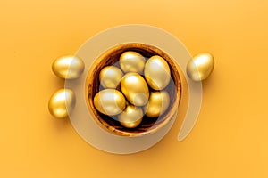 Golden Easter eggs in wooden bowl. Wealth and good luck concept.