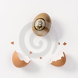 Golden egg with a bitcoin sign and eggshell on white background. Minimal investment concept