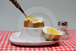 Golden egg in an egg cup on a red patterned napkin