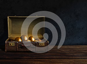 Golden eggs inside an old suitcase
