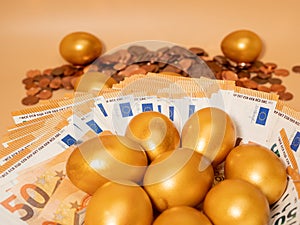 Golden eggs on money. Golden chicken eggs on euro banknotes and coins.