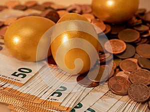 Golden eggs on money. Golden chicken eggs on euro banknotes and coins.