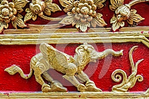 Golden Elephant with flowers, wings and claws on red wall