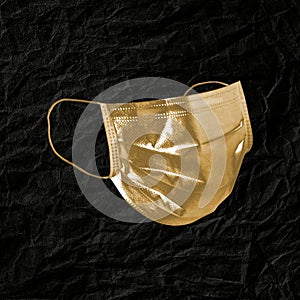 Golden face mask on a black leather textured background