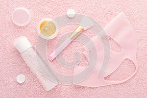 Golden facial cream mask with a brush, micellar water and silicone mask on pink