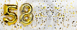 Golden foil balloon number, figure fifty-eight on white with confetti background. 58th birthday card. Anniversary