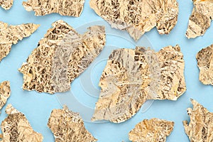 Golden foil pieces on blue abstract background, torn gold paper pattern