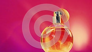 Golden fragrance bottle and shining light flares on pink background, glamorous perfume scent as holiday perfumery