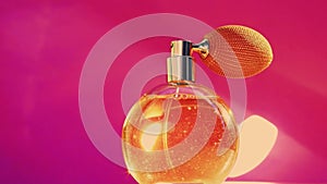 Golden fragrance bottle and shining light flares on pink background, glamorous perfume scent as holiday perfumery