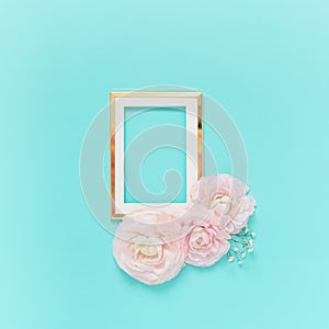 Golden frame with pink ranunculus flowers on light blue background. Holiday, greetings, love, romantic concept. Flat lay, copy