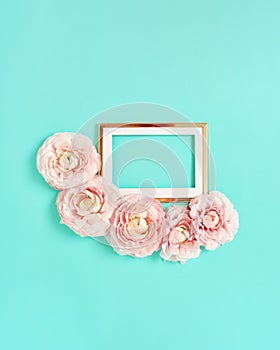 Golden frame with pink ranunculus flowers on light blue background. Holiday, greetings, love, romantic concept. Flat lay, copy