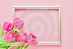 Golden frame with pink tulips on pink background. Mockup. Top view, copy space