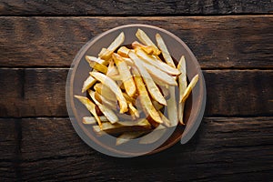 Golden fried potatoes (French fries) presented on a wooden table