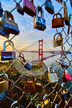 Golden Gate Bridge in California through hole in chain link fence covered in locks