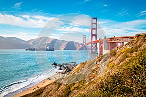 Golden Gate Bridge with cargo ship at sunset, San Francisco, California, USA