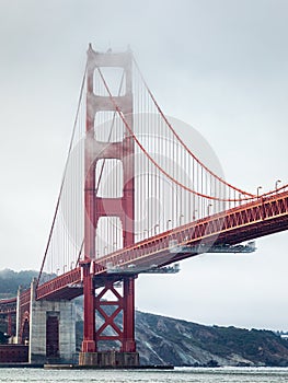 Golden gate bridge covered by fog at overcast sunrise