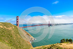Golden Gate Bridge with the skyline of San Francisco in the background on a beautiful sunny day with blue sky and clouds in summer