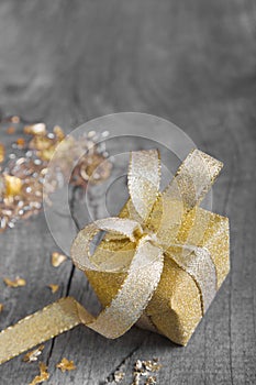 Golden gift box for christmas on a grey shabby chic background wi