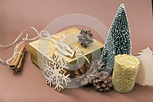 Golden gift box, cones, small Christmas tree, Golden candle, snowflake, cinnamon sticks on brown background, merry Christmas