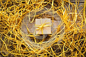 Golden gift box on wooden table with raffia or twine