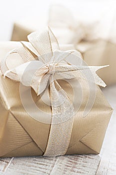 Golden gift boxes with beautiful ribbon and bow on a bright shin