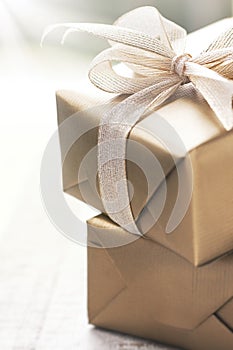 Golden gift boxes with beautiful ribbon and bow on a bright shiny background