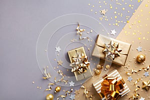 Golden gift or present boxes with golden bows and confetti top view. Christmas background. Flat lay style