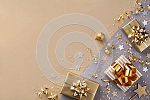 Golden gift or present boxes with golden bows and star confetti on bicolor background top view. Flat lay composition for Christmas