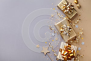 Golden gift or present boxes with golden bows and star confetti on bicolor background top view. Flat lay composition for Christmas