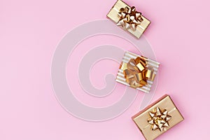 Golden gift or present boxes on pink background top view. Festive composition for birthday, christmas or wedding. Flat lay