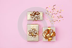 Golden gift or present boxes and star confetti on pink background top view. Flat lay for birthday, christmas or wedding.