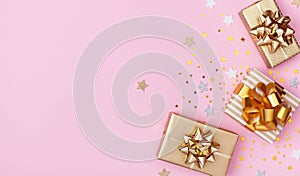 Golden gift or present boxes and star confetti on pink background top view. Flat lay for birthday, christmas or wedding