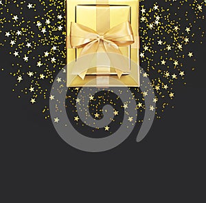 Golden gift with ribbon, confetti stars on black background. Flat lay, top view, copy space. Golden decorations, party, birthday,