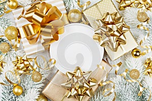 Golden gifts or presents boxes, paper blank, snowy fir tree and christmas decorations on white wooden table top view. Flat lay.