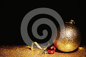 Golden glitter, Christmas balls and streamer against black background