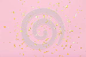 Golden glitter confetti sparkles on pastel pink background. Flat lay, top view. Holiday, festive, party backdrop.