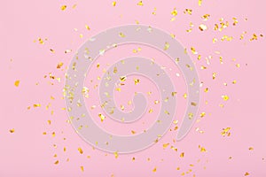 Golden glitter confetti sparkles on pastel pink background. Holiday, festive, party backdrop. Flat lay, top view, copy