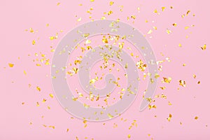 Golden glitter confetti sparkles on pastel pink background. Holiday, festive, party backdrop. Flat lay, top view, copy