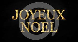 Golden glitter with the french words for merry christmas - joyeux noel on black chalkboard background