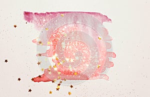 Golden glitter and glittering stars on abstract pink watercolor splash