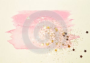 Golden glitter and glittering stars on abstract pink watercolor splash in vintage nostalgic colors.