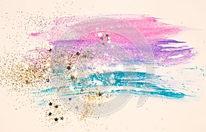 Golden glitter and glittering stars on abstract watercolor splash in vintage nostalgic colors.