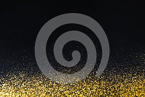 Golden glitter sand texture border on black, abstract background.