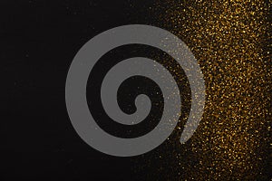 Golden glitter sand texture border on black, abstract background.