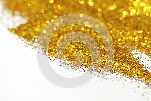 Golden glitter sand texture handful spread on white, abstract background with copy space