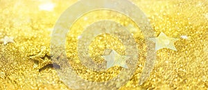 Golden glitter stars on yellow background. Gold shiny texture, copy space for your Christmas greetings. Concept of New year,