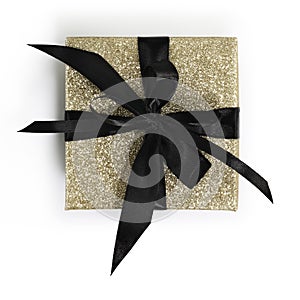 Golden glittering gift box package with black ribbon bow isolated on white background, top view